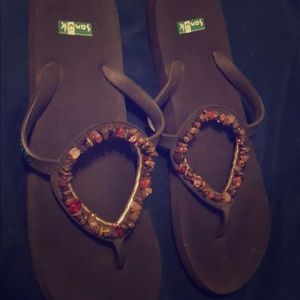 Sanuk flip-flops with pebble trim.